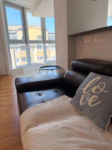 a leather couch in a living room with a large window at Matey Luxury Sky Apartment in Bitola