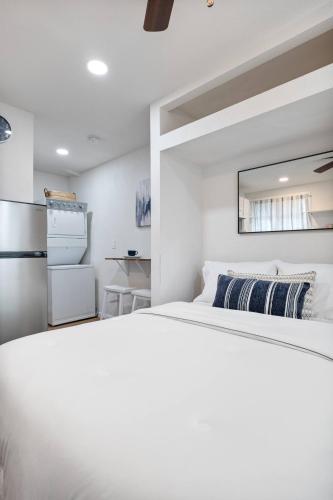 a white bedroom with a bed and a refrigerator at Le Petite Willow - Guesthouse in Modesto