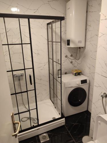 a shower in a bathroom with a washing machine at Lea Lux apartment Tuzla in Tuzla