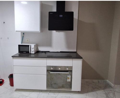 eine Küche mit einer Arbeitsfläche, an der eine Mikrowelle und ein Herd angebracht sind. in der Unterkunft Modern central flat in Ceuta