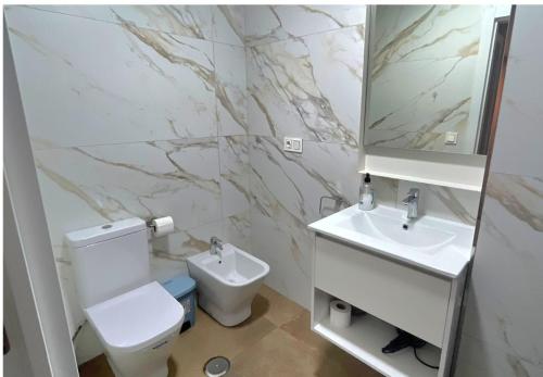 ein Badezimmer mit Toilette, Waschbecken und Spiegel in der Unterkunft Modern central flat in Ceuta