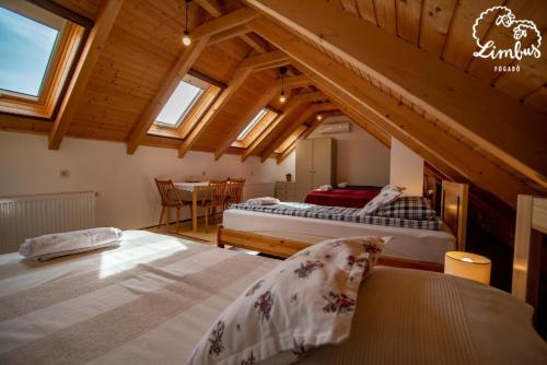 a attic room with two beds and a table at Limbus Fogadó in Gyöngyöstarján