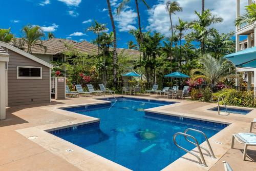 a pool with chairs and umbrellas next to a house at Grand Champions 185 in Wailea