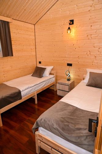 two beds in a room with wooden walls at EKA Resort in Goris