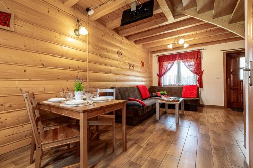 a dining room with a table and a couch at DW KINGA Domki całoroczne 6 os z widokiem na Tatry in Kacwin