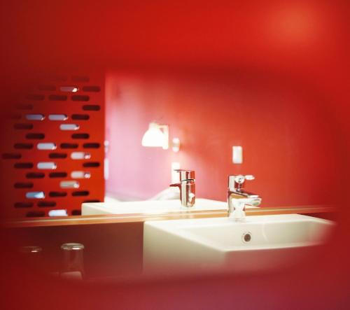 a bathroom with a sink and a red wall at Kyriad Vienna Altmannsdorf in Vienna