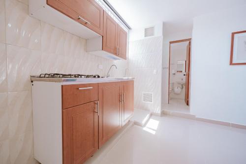eine Küche mit Holzschränken, Spüle und Badewanne in der Unterkunft Apartamento Edificio Neon Centro in Ibagué