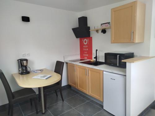 a small kitchen with a table and a microwave at Petite maison meublée in Landévant