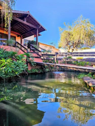 a wooden bridge over a river with a building at Hotel Vivenda das Cachoeiras in Brotas