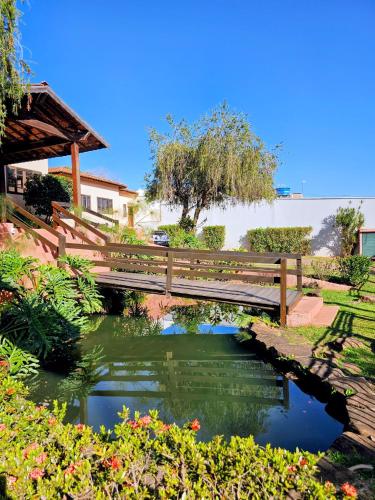 a wooden bridge over a pond in a garden at Hotel Vivenda das Cachoeiras in Brotas
