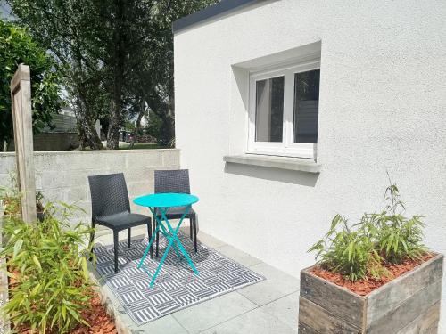 two chairs and a blue table on a patio at Petite maison meublée in Landévant
