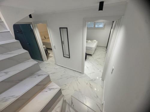 a white hallway with marble floors and a mirror at Eternity fresh in Limenaria