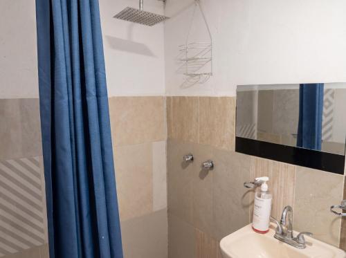a bathroom with a sink and a blue shower curtain at Barrio Antiguo Hostel HK in Monterrey