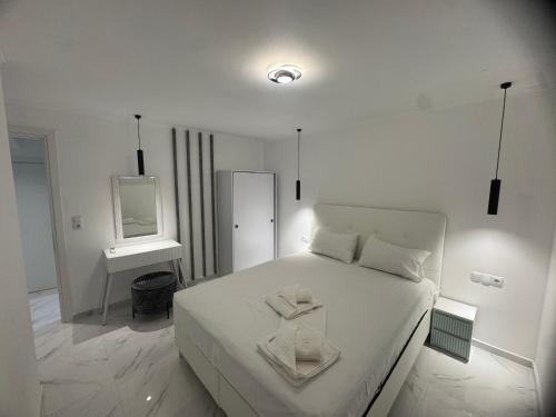a white bedroom with a bed and a mirror at Eternity fresh in Limenaria
