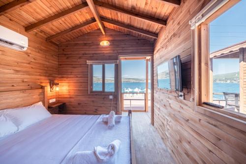 a bedroom with a bed in a wooden room with windows at Akyalı Boutique Hotel in Guvercinlik
