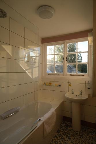 a white bathroom with a tub and a sink at The St Crispin Inn in Worth