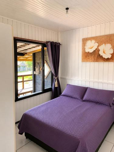 a bedroom with a purple bed and a window at Pousada Cristais do Rosa in Imbituba