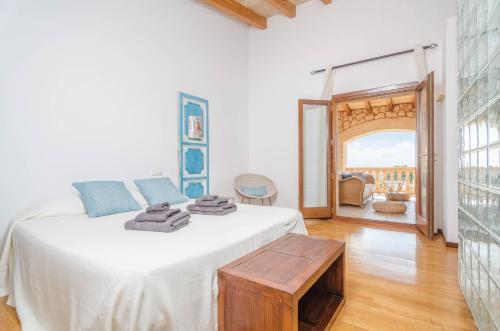 a white bedroom with a bed and a table at Can Teco in Porto Cristo