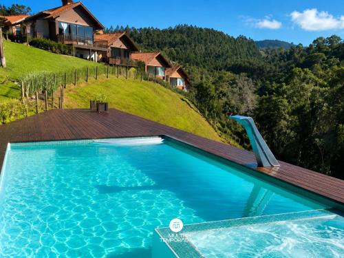 a swimming pool with a house on a hill at Pousada Dona Teresinha com Piscina Aquecida - São Bonifácio/SC in São Bonifácio