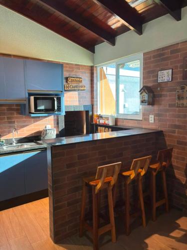 a kitchen with a bar with three stools at it at Casa Bioma da Chapada in Chapada dos Guimarães
