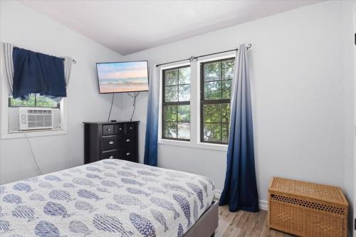 a bedroom with a bed and two windows and a television at Private Dock, Boat Launch, Fire Pit & Lake Views in Sunrise Beach