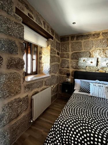 a stone walled bedroom with a bed and a window at Caneliña in Ourense