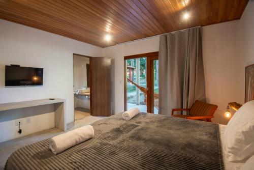 a bedroom with a large bed with a television on the wall at Villaflor Pousada in Vale do Capao