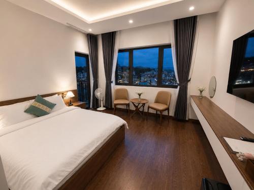 a hotel room with a large bed and windows at Saffron Boutique Hotel in Da Lat