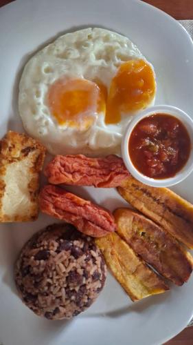 a white plate with an egg and other breakfast foods at exotic island ometepe in Altagracia