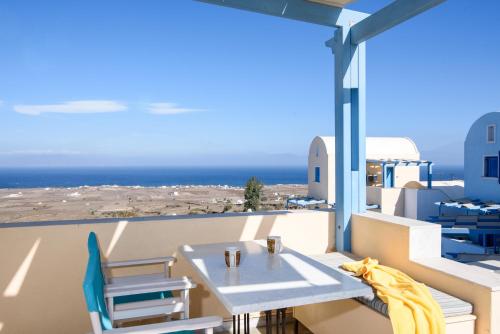a table and chairs on a balcony with a view of the ocean at Maria's Place - Adults Only in Oia