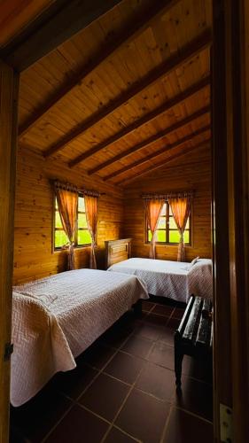 two beds in a wooden room with windows at Glamping Store in Guatavita