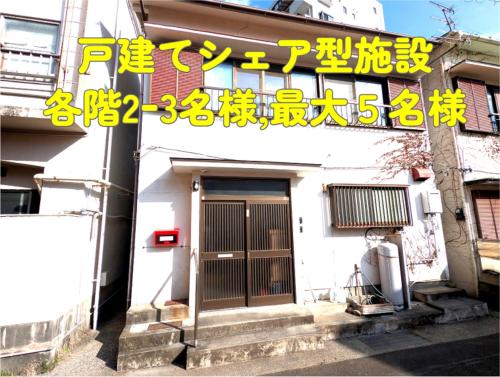 a building with a door with a sign on it at Apt南熱海-網代 in Atami