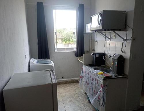 a room with a kitchen with a tv on a wall at Estúdio 800m do Buriti Shopping in Aparecida de Goiânia