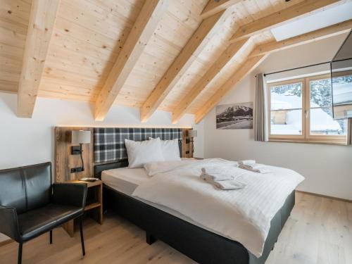 a bedroom with a large bed and a chair at Donnersbach Lodge in Donnersbachwald