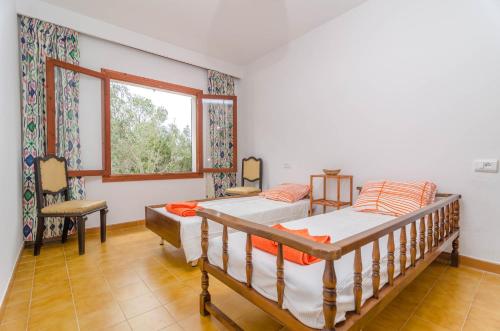 two beds in a room with a window at Es Jaç in Cala Santanyi