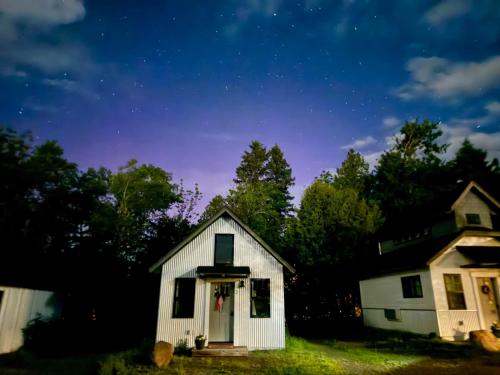 a small white house with a starry sky at The Summit Suite | Walk to Rangeley Lake • ATV & Sled Access in Rangeley