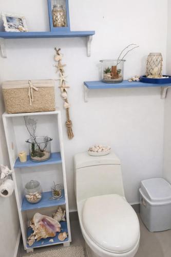 a bathroom with a white toilet and blue shelves at Trade winds International in Progreso