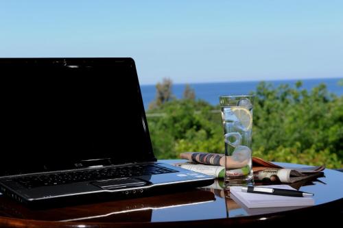 a laptop computer sitting on a table with a glass at Delfinia Hotel & Bungalows in Mithymna