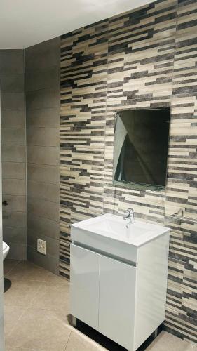a bathroom with a sink and a tv on a wall at Villa Pérola Pestana in Lourinhã