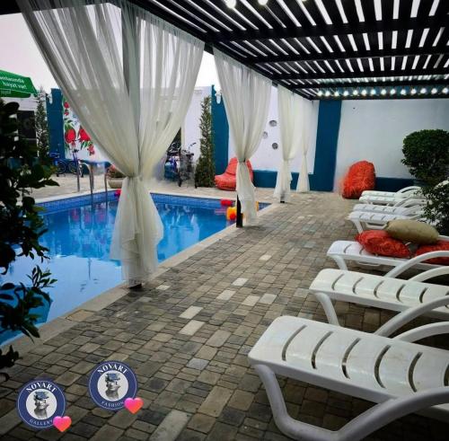 a pool with white curtains and chairs next to a pool at Caspian Seaside Hotel in Sumqayıt