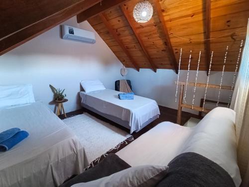 a bedroom with two beds and a wooden ceiling at Chalés Cabocla da Lua in Caraíva