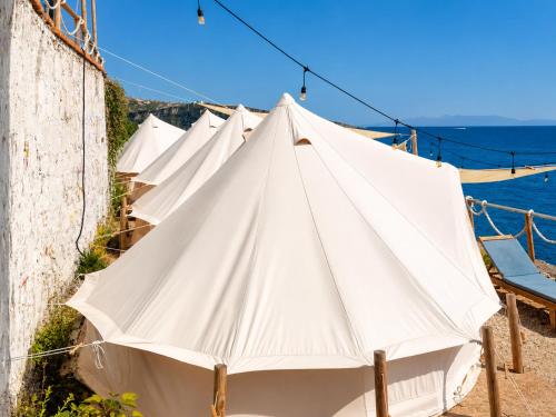 a row of white tents next to the water at Albania Glamping in Himare