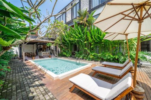 an outdoor pool with two chairs and an umbrella at Sebelas Apartments by EVDEkimi - Modern Stay with Pool near Dining & Shops in Ubud