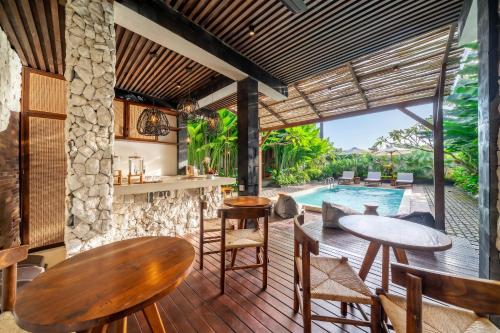 a patio with tables and chairs and a swimming pool at Sebelas Apartments by EVDEkimi - Modern Stay with Pool near Dining & Shops in Ubud