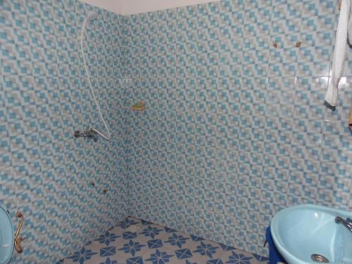 baño con paredes de azulejos azules y lavabo en La Paillotte, en Palimé