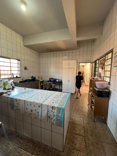 a person standing in a kitchen with a refrigerator at ''Pousada Rosa Amiga'' in Barretos
