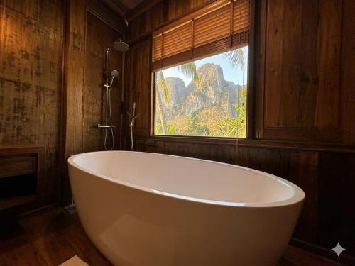 a large white bath tub in a room with a window at Cabalina Grove in Ðảo Cát Bà