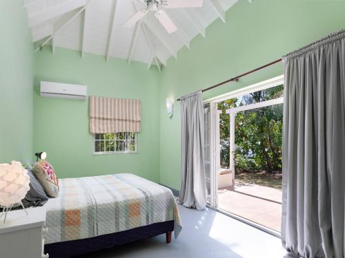 a bedroom with green walls and a bed and a sliding glass door at Stunning Views Oceanfront Oasis with Private Pool - Inch by Inch in Christ Church