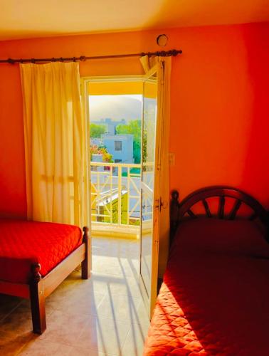 a room with two beds and a door to a balcony at Hotel el Progreso in Olta