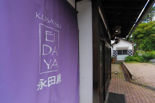 a purple wall with a sign on the side of a building at Kusatsu Onsen Eidaya in Kusatsu